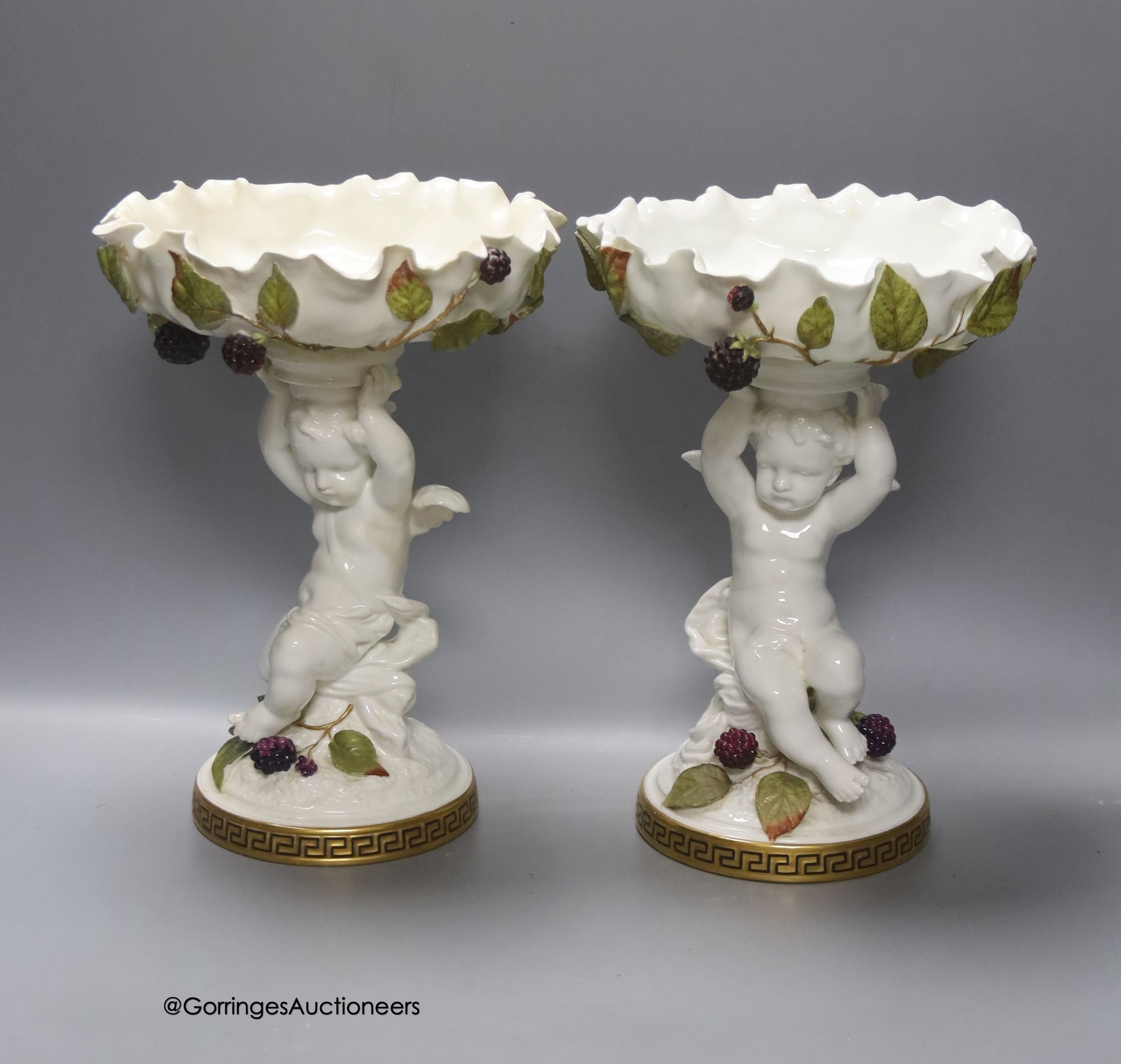 A pair of Moore Bros leaf pattern bowls, encrusted with fruit and surmounted by cherubs and a similar pair of tazza stands, height 24cm